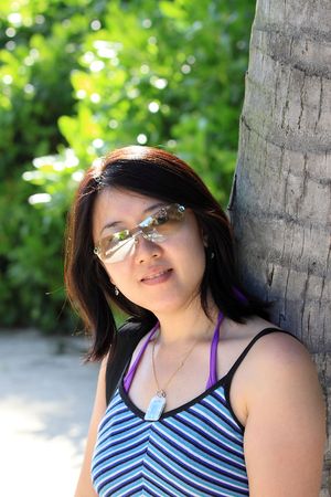 Portrait of an Asian woman leaning against a coconut treeの写真素材