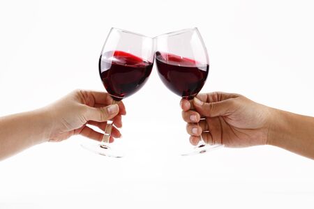 Two people toasting with wine glasses filled with red wineの写真素材