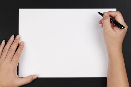 A woman's hand with a pen and paper on a black backgroundの写真素材