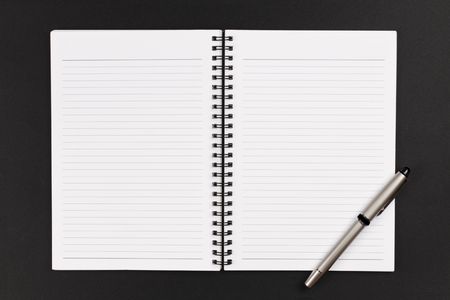 A pen and a notebook on a black backgroundの写真素材