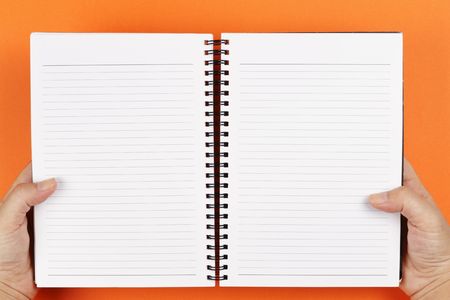 A pair of hands holding an open notebookの写真素材