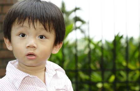 A curious looking Asian boy at a parkの写真素材