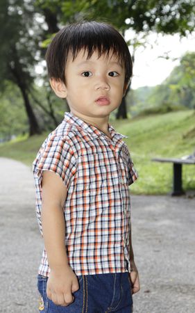 An Asian boy standing at a public park