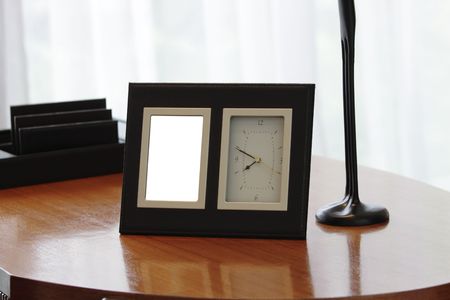 A modern photo frame and a clock on a wooden tableの写真素材