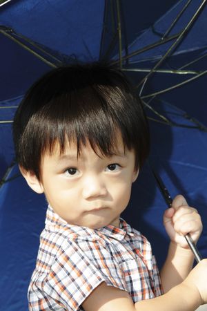 A young Asian boy holding an umbrellaの写真素材