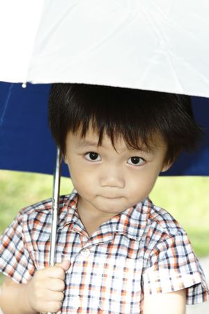 A young Asian boy holding an umbrellaの写真素材