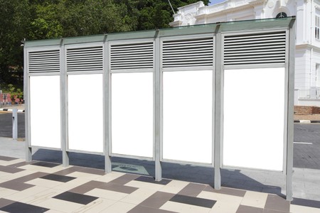Rear view of a bus stop with a row of blank billboards. 