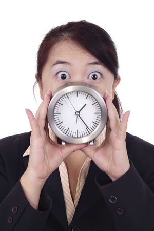 An Asian businesswoman looking shocked and holding a table clockの写真素材