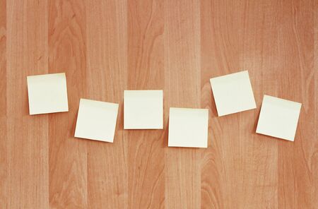 A row of post-it notes pasted on a wooden wallの写真素材