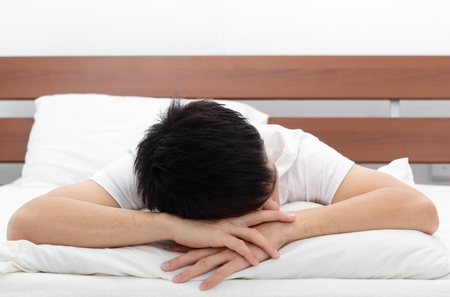 An Asian man sleeping faced down