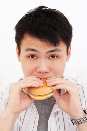 A young Asian man biting into a burgerの写真素材