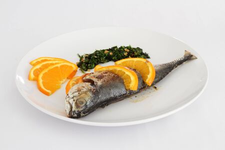 A plate of Torpedo Scad fish served with sliced lemon, parsley and salsa verdeの写真素材