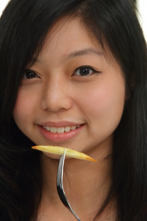 An Asian woman holding up a piece of french friesの写真素材