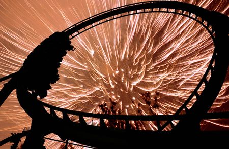 Some people on a rollercoaster at night illuminated in silhouette