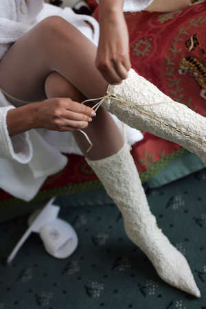 Bride in a traditional white wedding dress tying her boot lacesの写真素材
