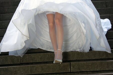 Bride in a traditional white wedding dress walking down some steps.の写真素材
