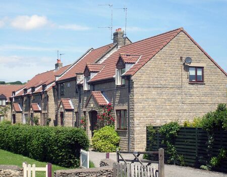 Modern English house end of terrace by village green.