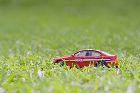 A child's small red fire car discarded in the grassの写真素材