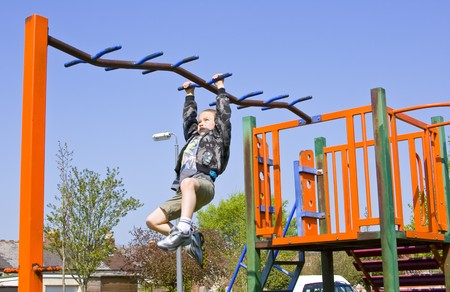 Young six year old boy plays on the equipment in a children's playpark