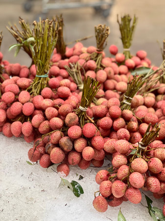 a photography of a pile of longan sitting on top of a table, arafficial bunch of longan sitting on a table with a bunch of leavesの写真素材