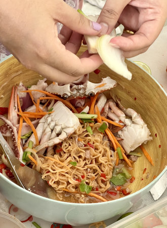 a photography of a person is putting a piece of food in a bowl, someone is putting a piece of food in a bowl with noodlesの写真素材