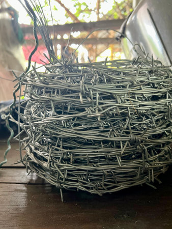 a photography of a bunch of barbed wire wrapped around a laptop, there is a large pile of barbed wire on a tableの写真素材