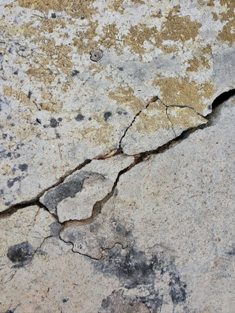 stone wall with cracks and cracks in it with a yellow and white paint.の写真素材