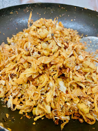 a photography of a pan filled with fried food and a spoon, dish of fried onions and onions in a frying pan.の写真素材