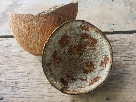 a photography of a coconut shell and a bowl on a wooden table, there is a coconut shell and a bowl...