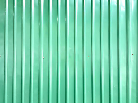 a photography of a green metal wall with a fire hydrant, green metal wall with a fire hydrant in front of it.の写真素材
