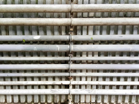 a photography of a metal grate with a bunch of pipes, there is a close up of a metal grate with a green plant growing out of it.の写真素材
