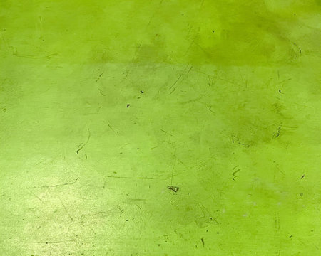 a photography of a skateboarder is riding on a green surface, green wall with a small black dot on it.の写真素材