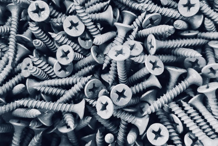 a photography of a pile of screws and bolts in black and white, a close up of a pile of screws and nails on a table.の写真素材