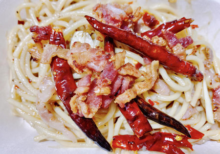 a photography of a plate of pasta with bacon and peppers, carbonara with bacon and peppers on a plate of pasta.の写真素材