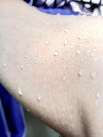 a photography of a person with a wet arm and a blue shirt, sun blocker on a person's arm with water...