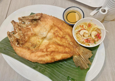 a photography of a plate of food with a bowl of soup and a fish.