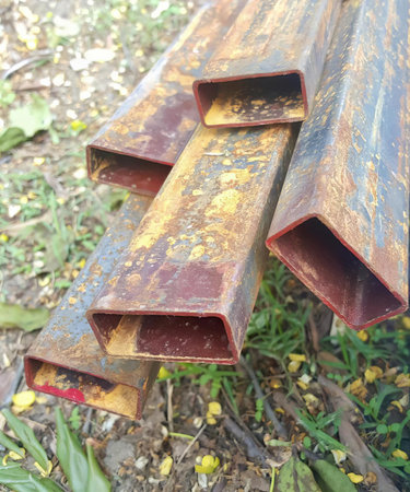 a photography of a pile of rusty pipes sitting on the ground, lumbermill with rust and rusted metal pipes laying on the ground.の写真素材