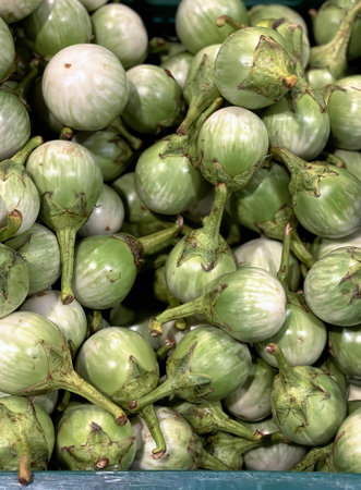 a photography of a pile of green vegetables in a blue container, globe artichokes are piled in a blue bin at a market.の写真素材