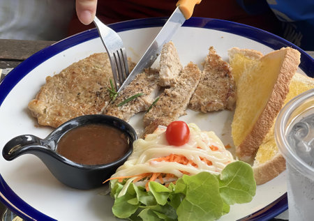 a photography of a plate of food with a fork and knife, plate of food with a fork and knife and a bowl of sauce.の写真素材