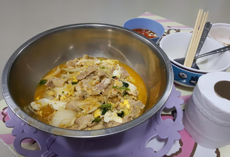 a photography of a bowl of food with chopsticks and a roll of toilet paper.の写真素材