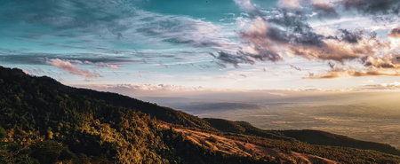 a photography of a view of a mountain with a sunset, alp of a mountain with a view of a valley and a cloudy sky.の写真素材