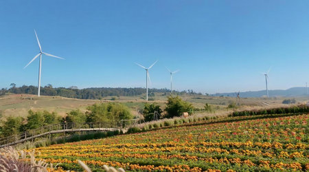 a photography of a field of flowers and wind turbines in the distance.