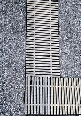 a photography of a wooden floor with a metal grate on it, manhole cover on the ground with a wooden slatt.の写真素材