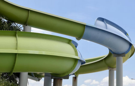 a photography of a green and blue water slide going down a hill, fountain with a green and blue...