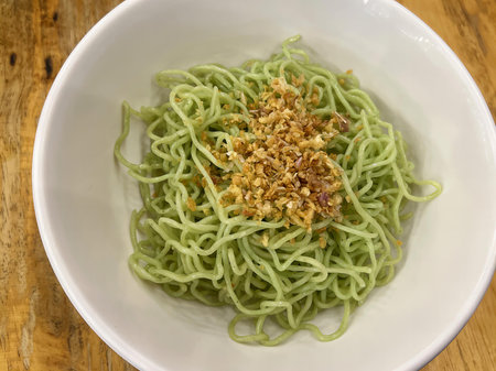 a bowl of green noodles with nuts..