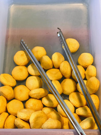 a photography of a container filled with lemons and tongs.の写真素材