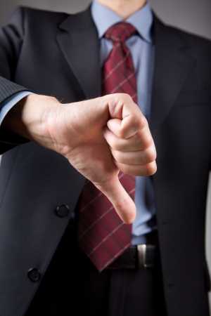 Well-dressed businessman showing disapproval thumbs down signの写真素材