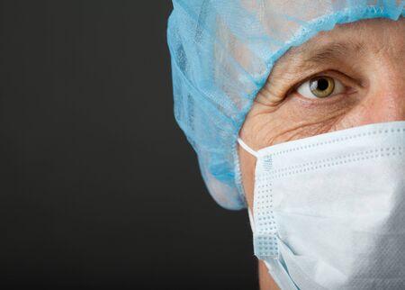 Doctor s face with mask and cap on grey backgroundの写真素材