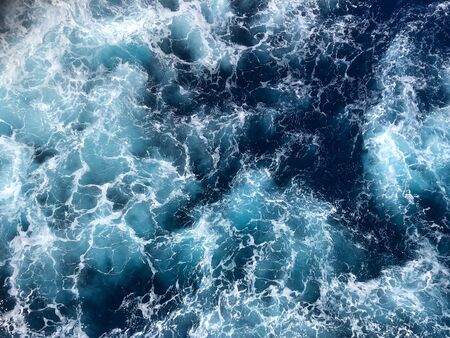 Small blue ocean waves with white caps forming from the a ship in the water