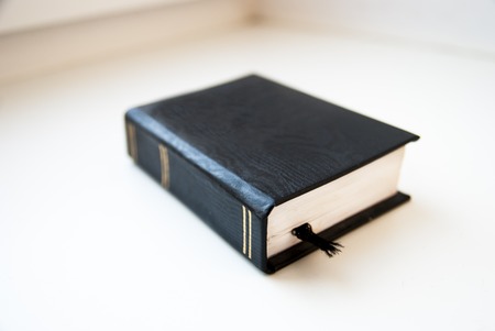Small black book with bookmark lying at the white surface.の写真素材